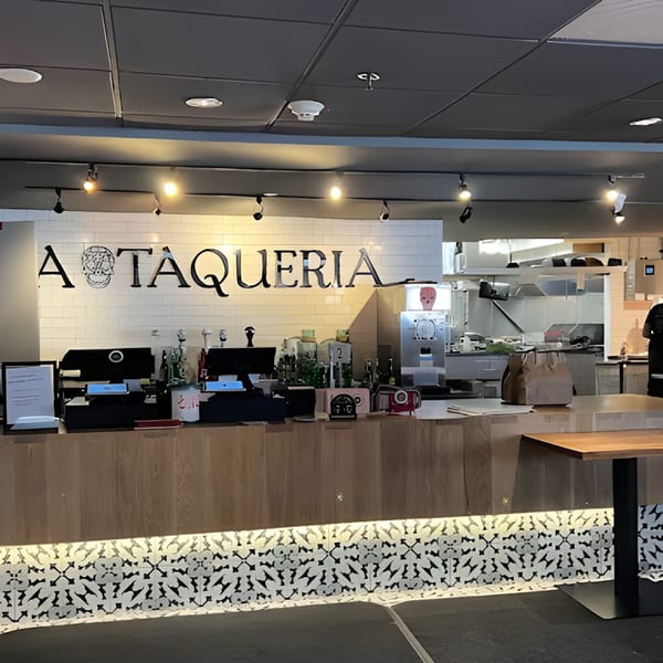 La Taqueria restaurant interior with a wooden counter, white tiled wall, and skull logo.