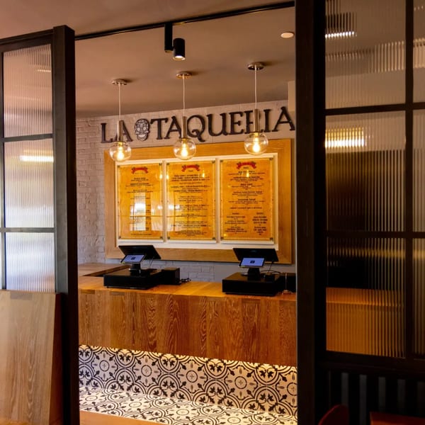 La Taqueria's ordering counter with menu boards, two POS systems, and decorative tiles.
