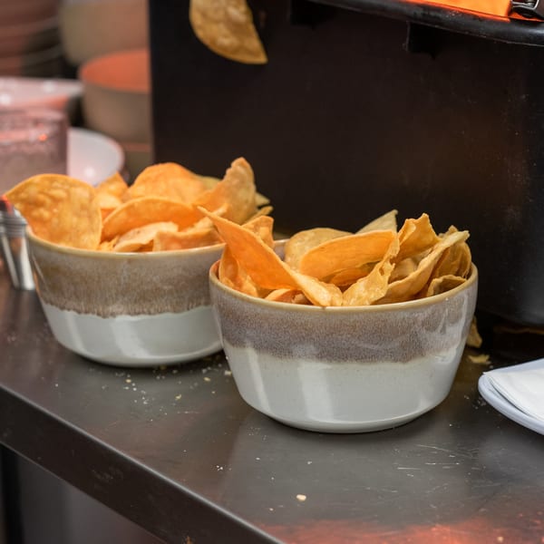 Two bowls of crispy tortilla chips on a dark counter at La Taqueria.