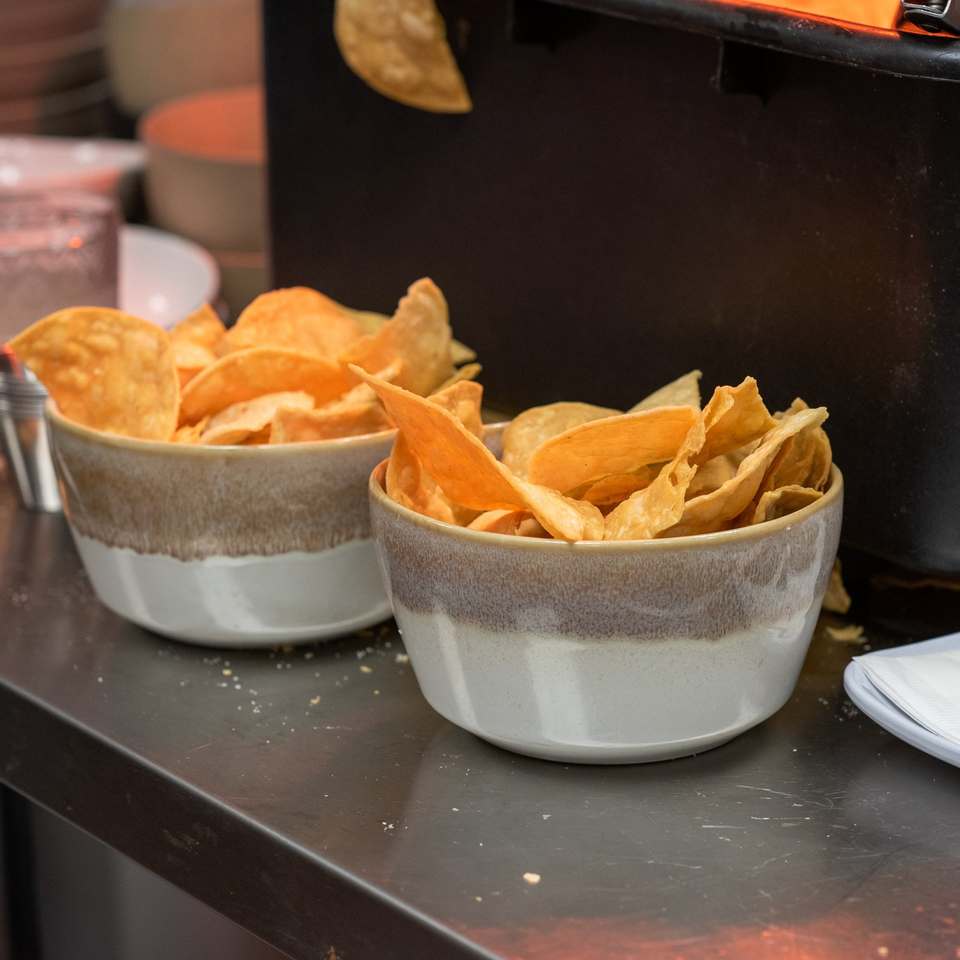 Two bowls of crispy tortilla chips on a dark counter at La Taqueria.