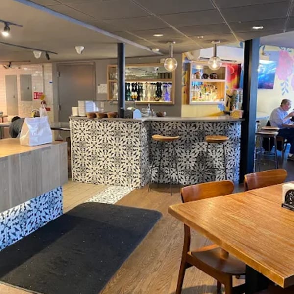 Interior of La Taqueria, featuring a patterned bar, wooden tables, and a customer dining.