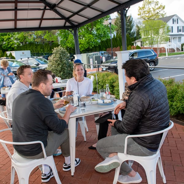 Group of people enjoying Mexican food and drinks at an outdoor patio table at La Taqueria.