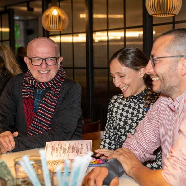 Three happy customers laughing together at a table in La Taqueria restaurant.